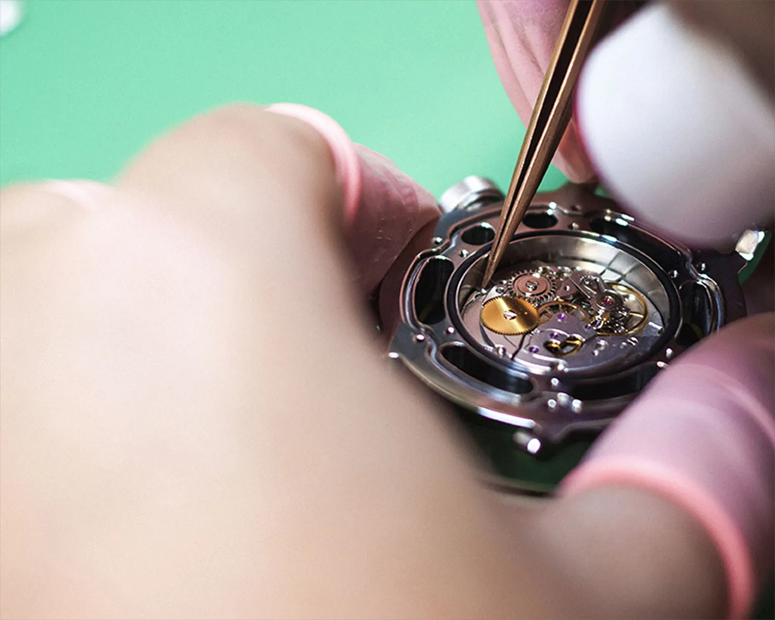Tweezers placing a component into the watch caseback